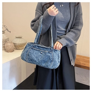 Close-up of vintage wash denim shoulder bag with decorative stitching and metal button