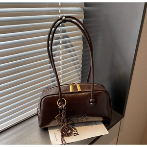 Detail of dark brown glossy leather shoulder bag with gold zipper and logo embossing
