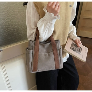 Detailed side view of canvas tote bag showing side pocket and brown ribbon handles