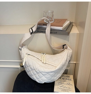 Détail du sac matelassé blanc montrant les pompons zippés et la bandoulière large