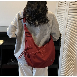 Macro detail of wine red crescent shoulder bag featuring ruched drawstring design