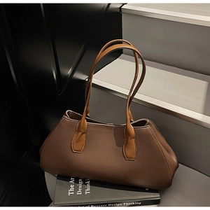 Detail of dark brown lychee grain leather tote bag placed on a book in minimalist setting