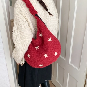 Detail of red plush shoulder bag featuring a white star patch and drawstring closure