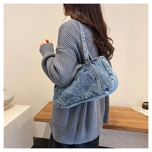 Detail of washed blue denim shoulder bag showing distressed texture and wide strap