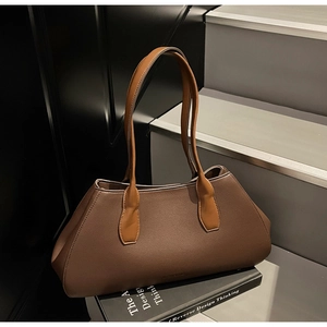 Detail of minimalist tote bag in brown pebbled leather on a modern book display