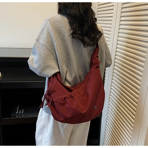 Close-up of wine red crescent bag with drawstring pleats and adjustable strap