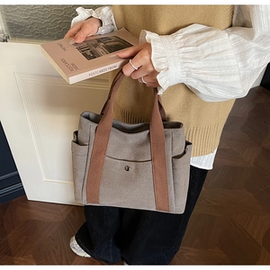 Detail of grey canvas tote bag with brown straps and side pocket for daily commuting