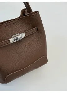 Detail view of brown pebbled leather bucket bag with silver metal buckle closure