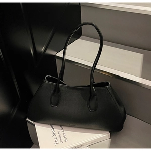 Detail of minimalist black tote bag with litchi texture leather on grey stairs