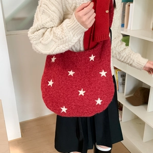 Detailed texture of red plush shoulder bag featuring white star patterns in soft lighting