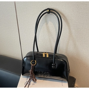 Close-up of black retro shoulder bag with gold dual zippers and brand embossing detail