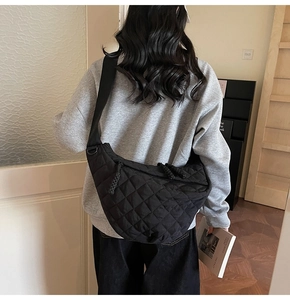 Détail d'un sac à bandoulière matelassé noir avec une large sangle sur le dos