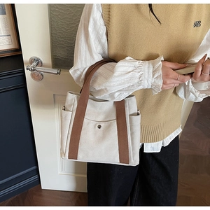 Detail of canvas tote bag with brown webbing handles and functional side pockets
