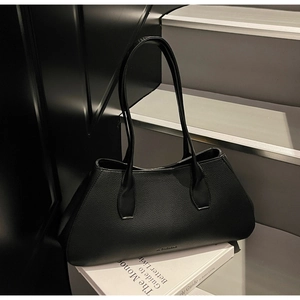 Macro detail of black lychee grain leather tote bag showing fine texture and embossed logo