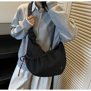 Detail view of black nylon crescent bag with drawstring ruching and wide strap