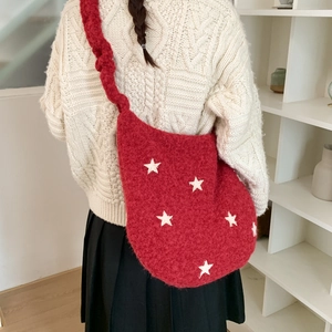 Detail of red plush hobo bag with white stars and soft knitted texture on shoulder