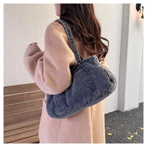 Detail of dark grey washed denim crossbody bag featuring contrast white stitching