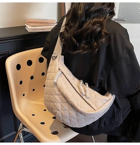 Gros plan du sac croissant beige matelassé avec tirette de fermeture tressée