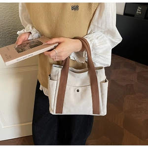 Detail view of canvas tote bag with brown straps and functional side pockets