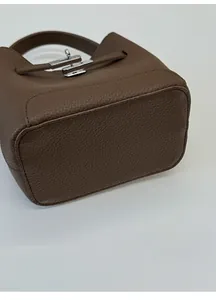 Detailed bottom view of brown litchi leather bucket bag with reinforced base and silver lock