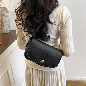 Detalle de bolso de hombro en cuero granulado negro con elegante cierre giratorio plateado