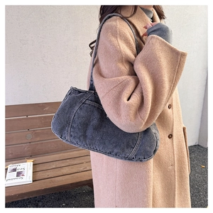 Detail shot of vintage washed denim shoulder bag on model with retro streetwear style