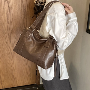 Detail of a dark brown large tote bag in glossy PU leather with silver metal hardware