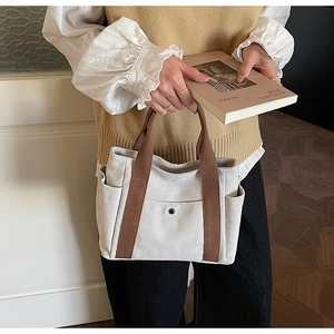 Detail view of large canvas tote bag with side pockets and brown webbing handles