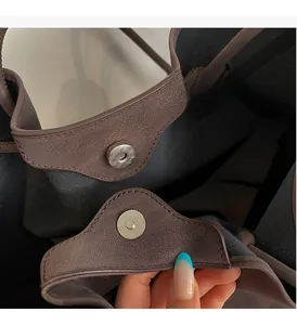Close-up of the vintage brown leather tote showing the silver magnetic snap button closure