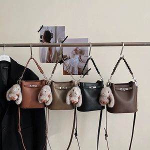 Détail de quatre sacs seaux en cuir grainé avec anses tressées et breloques lapins