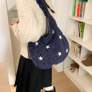 Blue plush hobo bag with white star pattern shown on model in a cozy indoor setting