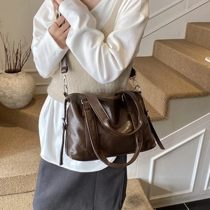 Detail of dark brown faux leather tote with oily texture and adjustable shoulder strap