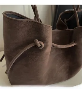 Close-up of brown frosted faux leather tote with vintage strap and knotted detail