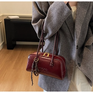 Detail of burgundy vintage oil wax leather boston bag with premium gold zipper and logo