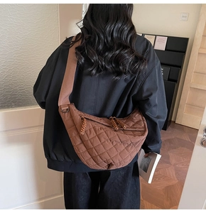Détail d'un sac demi-lune marron matelassé avec large bandoulière et tirette de zip tissée