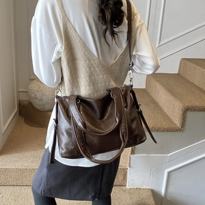 Rear view of a large vintage dark brown tote bag worn on shoulder by a model