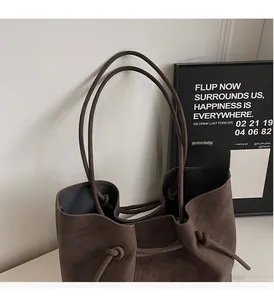 Close-up of matte dark brown leather tote bag with unique drawstring knot detail