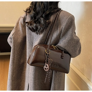 Detail of dark brown leather bowling bag with side embossing and decorative charm