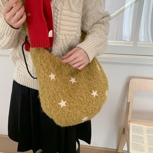 Close-up of yellow plush hobo bag featuring white star patches and soft fuzzy texture