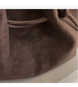 Macro detail of dark brown leather texture and soft pleats on a stylish tote bag