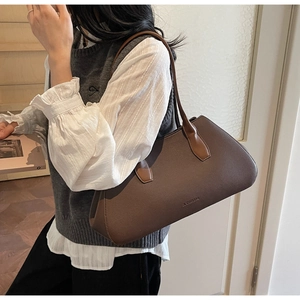 Close-up of minimalist brown litchi pattern leather tote bag with brand logo embossing