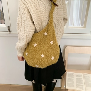Model shows ginger yellow plush shoulder bag with white star patches and pleated texture