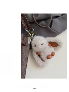 Porte-clés lapin en peluche grise avec détails en cuir sur un sac à bandoulière