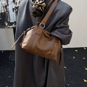 Detail of caramel brown leather tote bag showing reinforced X-stitching and smooth texture