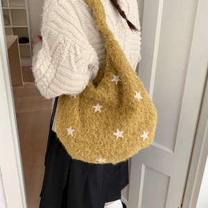 Close-up of yellow plush tote bag with star embroidery worn on shoulder for winter