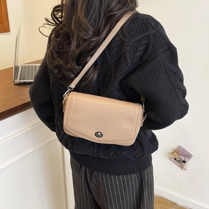 Detalle de bolso de hombro beige en cuero granulado con cierre de hebilla plateada