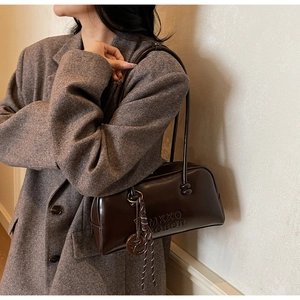 Macro shot of dark coffee shiny leather bag with embossed logo and knotted charm detail