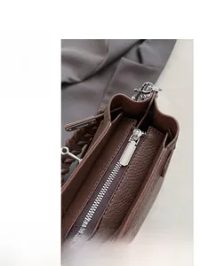 Gros plan sur le cuir marron texturé avec poignée tressée et fermeture éclair argentée chic