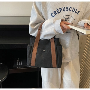 Detail of black canvas tote bag showing side pockets and brown handles in daily use