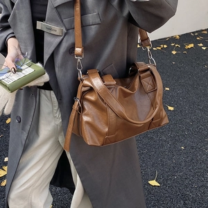 Close-up of brown vintage Boston bag with adjustable strap and textured leather finish
